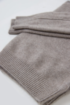 A folded cashmere knit sweater in a heathered taupe-grey colour, showing the ribbed cuff and soft texture on a plain white background.